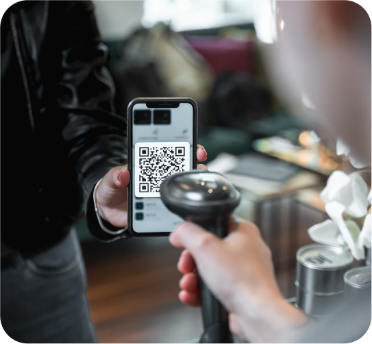 A person scans a QR code from a smartphone screen with a handheld scanner